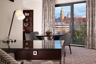 a living room with a table and a large window at Sheraton Grand Krakow in Kraków