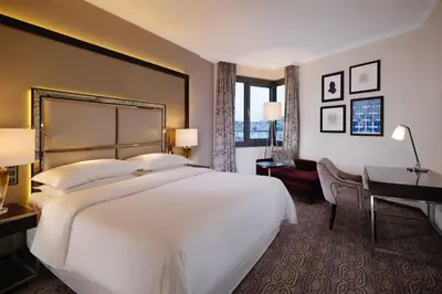 a hotel room with a large bed and a desk at Sheraton Grand Krakow in Kraków