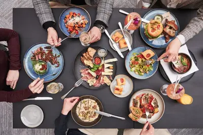 a group of people sitting around a table eating food at Sheraton Grand Krakow in Kraków