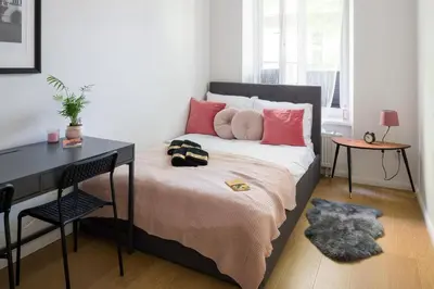 a bedroom with a bed with pink pillows and a desk at Powiśle 4 by Homeprime in Kraków