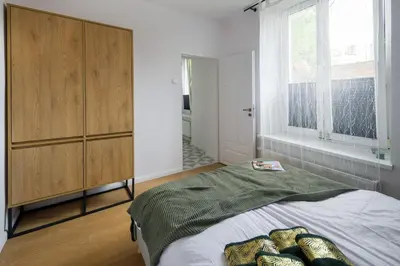 a bedroom with a bed and a wooden cabinet at Powiśle 4 by Homeprime in Kraków