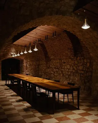 a long wooden table in a room with a brick wall at Hotel Pod Różą in Kraków