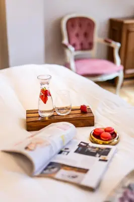 a table with two glasses and a book on a bed at Hotel Rubinstein in Kraków