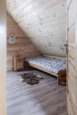 a bed in a wooden room with a wooden floor at Jodłowa Chata in Myślenice