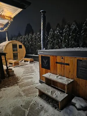 a wooden cabin with a bench in the snow at Jodłowa Chata in Myślenice