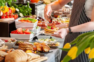 a woman is serving food at a buffet at Spatz Aparthotel in Kraków