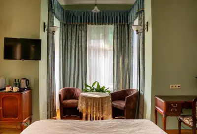 a bedroom with a bed and two chairs and a window at Hotel Polonia in Kraków