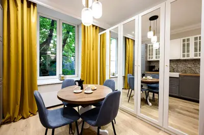 a dining room with yellow curtains and a table and chairs at Native Apartments Nowowiejska 9 in Kraków