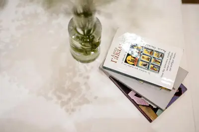 a book and a vase on a table with a bottle at Native Apartments Nowowiejska 9 in Kraków