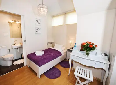 a small room with a bed and a desk and a sink at Hotel Mikołaj in Kraków
