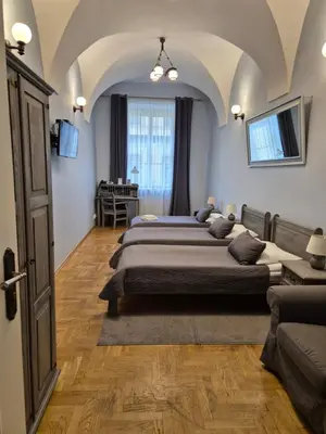 a bedroom with two beds and a table at Hotel Mikołaj in Kraków