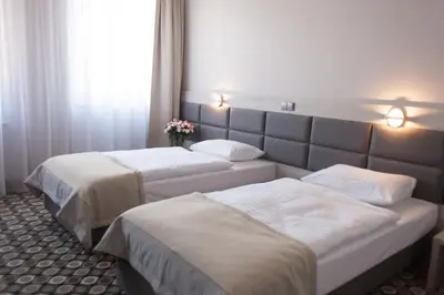 two beds in a hotel room with flowers on the wall at Piwnica Rycerska Kęty in Kęty