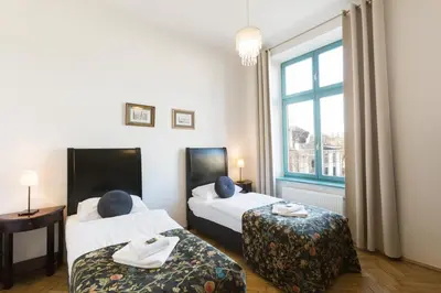 a hotel room with two beds and a window at Antique Apartments Plac Szczepański in Kraków