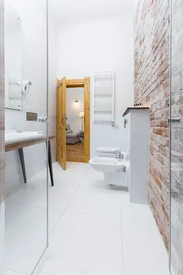 a bathroom with a brick wall and a sink and a toilet at Antique Apartments Plac Szczepański in Kraków