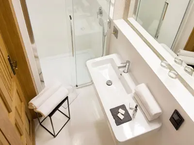 a white bathroom with a sink and a shower at Antique Apartments Plac Szczepański in Kraków