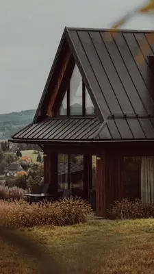 a house with a black roof and windows at oto.domki in Rokiciny Podhalanskie