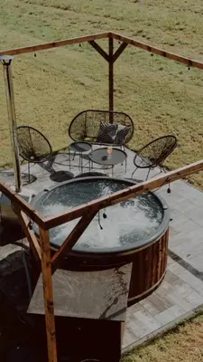 a patio with a hot tub and a table and chairs at oto.domki in Rokiciny Podhalanskie