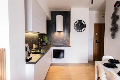 a kitchen with white cabinets and black counter tops at Forest 21 by Housine in Zator
