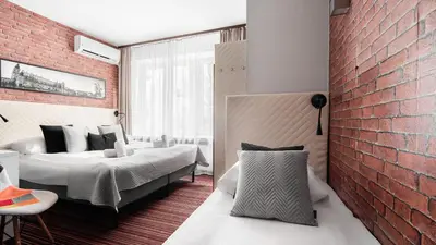 a bedroom with two beds and a brick wall at Hotel Delta in Kraków