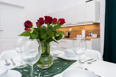 a table with a vase with red roses in it at Szpitalna Premium Apartment in Kraków