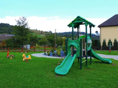a playground with a green slide in the grass at Apartamenty Suzyw Pilsko in Pewelka