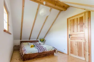 a bedroom with a bed and a wooden door at Domki Pod Dębem in Błądzonka