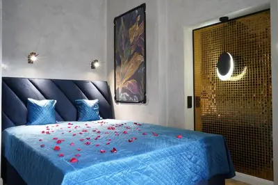 a bedroom with a blue bed with red roses on it at Apartament z Jacuzzi w Sercu Krakowa in Kraków