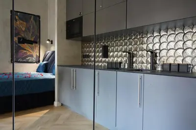 a kitchen with white cabinets and a bed in a room at Apartament z Jacuzzi w Sercu Krakowa in Kraków