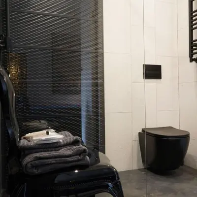 a bathroom with a black chair and a toilet at Apartament z Jacuzzi w Sercu Krakowa in Kraków
