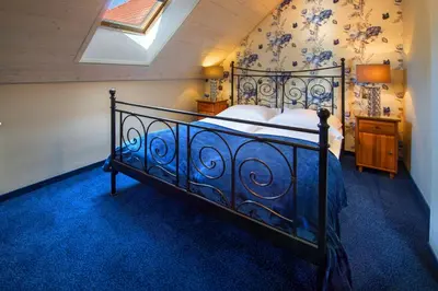 a bedroom with a large bed with a blue carpet at Hotel Zalesie in Bochnia