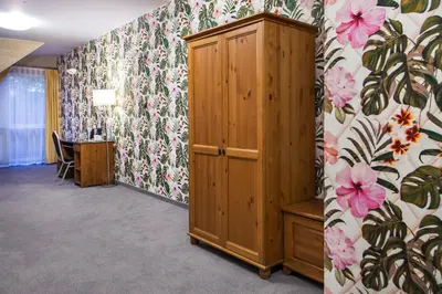 a room with a wooden cabinet and floral wallpaper at Hotel Zalesie in Bochnia