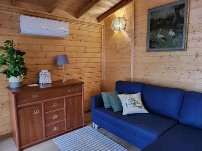 a living room with a blue couch and a wooden wall at Domki na Górniej Łące - Domek Słowik in Łazany