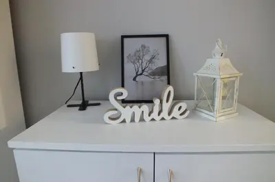 a white dresser with a smile sign and a lamp at Apartamenty Nila in Kraków