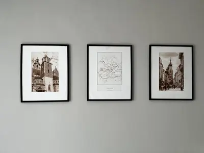 three framed pictures on a wall with drawings of cities at Apartamenty Nila in Kraków