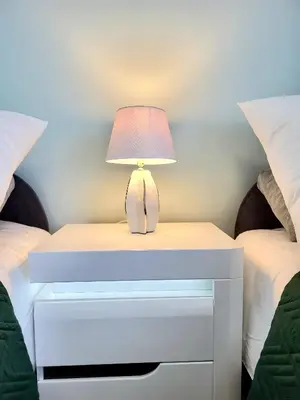 a bedside table with a lamp on it next to two beds at Eksclusive Apartment PARADISE DOWN TOWN 6 persons 3 rooms in Kraków