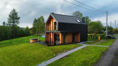 a house with a black roof on a green field at Wood Lake Rożnów in Rożnów