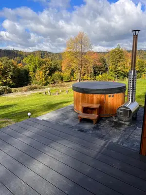 a hot tub sitting on a deck next to a field at Wood Lake Rożnów in Rożnów