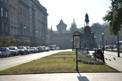 a city street with parked cars and a statue of a person at Red Brick Apartments in Kraków