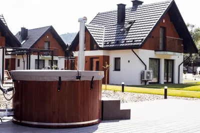 a large wooden tub in front of a house at Dolina Barw - całoroczne domki na wynajem in Rabka