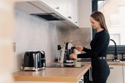 a woman standing in a kitchen with a coffee maker at Dolina Barw - całoroczne domki na wynajem in Rabka