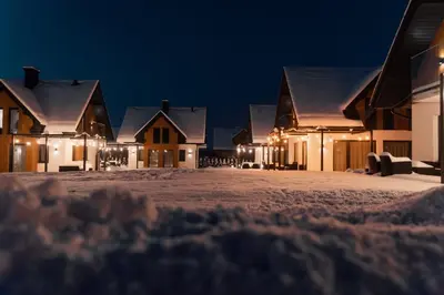 a group of houses at night in the snow at Dolina Barw - całoroczne domki na wynajem in Rabka