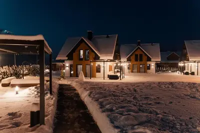 a group of houses in the snow at night at Dolina Barw - całoroczne domki na wynajem in Rabka