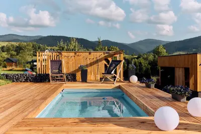 a swimming pool on a wooden deck with a house at Gorczańskie Wzgórze in Niedźwiedź