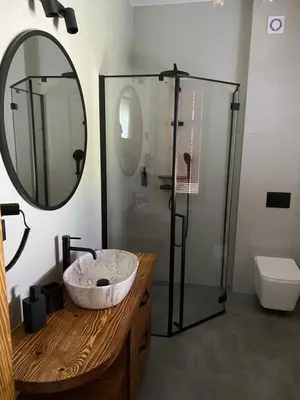 a bathroom with a sink and a glass shower at Apartamenty Zander in Zator