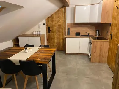 a kitchen with a wooden table and chairs at Apartamenty Zander in Zator