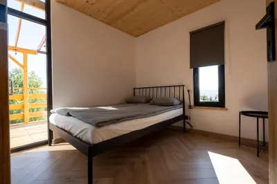 a bedroom with a bed and a large window at Domki Jasicówka pod Łysą Górą in Limanowa