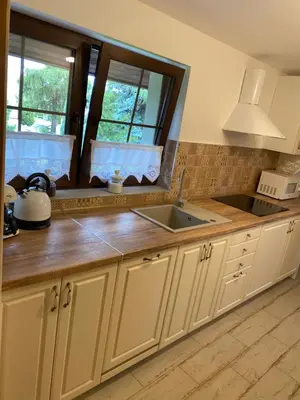 a kitchen with white cabinets and a sink and a window at Lu Residence - Unique Apartments in Oświęcim