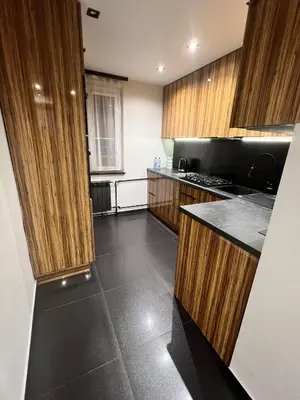 a kitchen with wooden cabinets and a black floor at V&O Apartament Old Town Kazimierz in Kraków