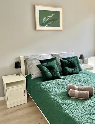 a bed with green sheets and pillows in a room at Modern Green Apartment in Kraków