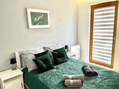 a bedroom with a bed with green sheets and pillows at Modern Green Apartment in Kraków